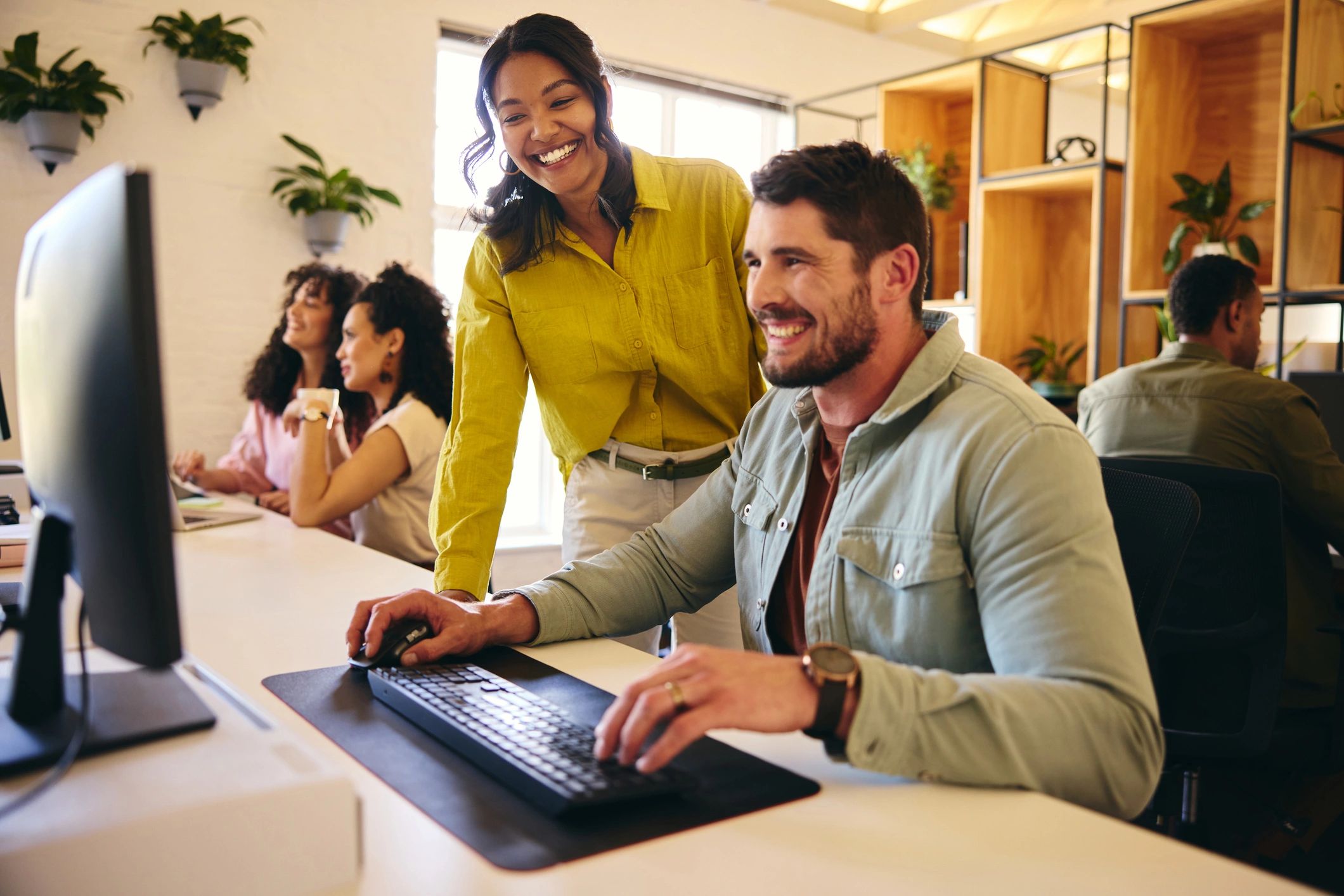 Friendly support team helping a customer with a chatbot on a computer